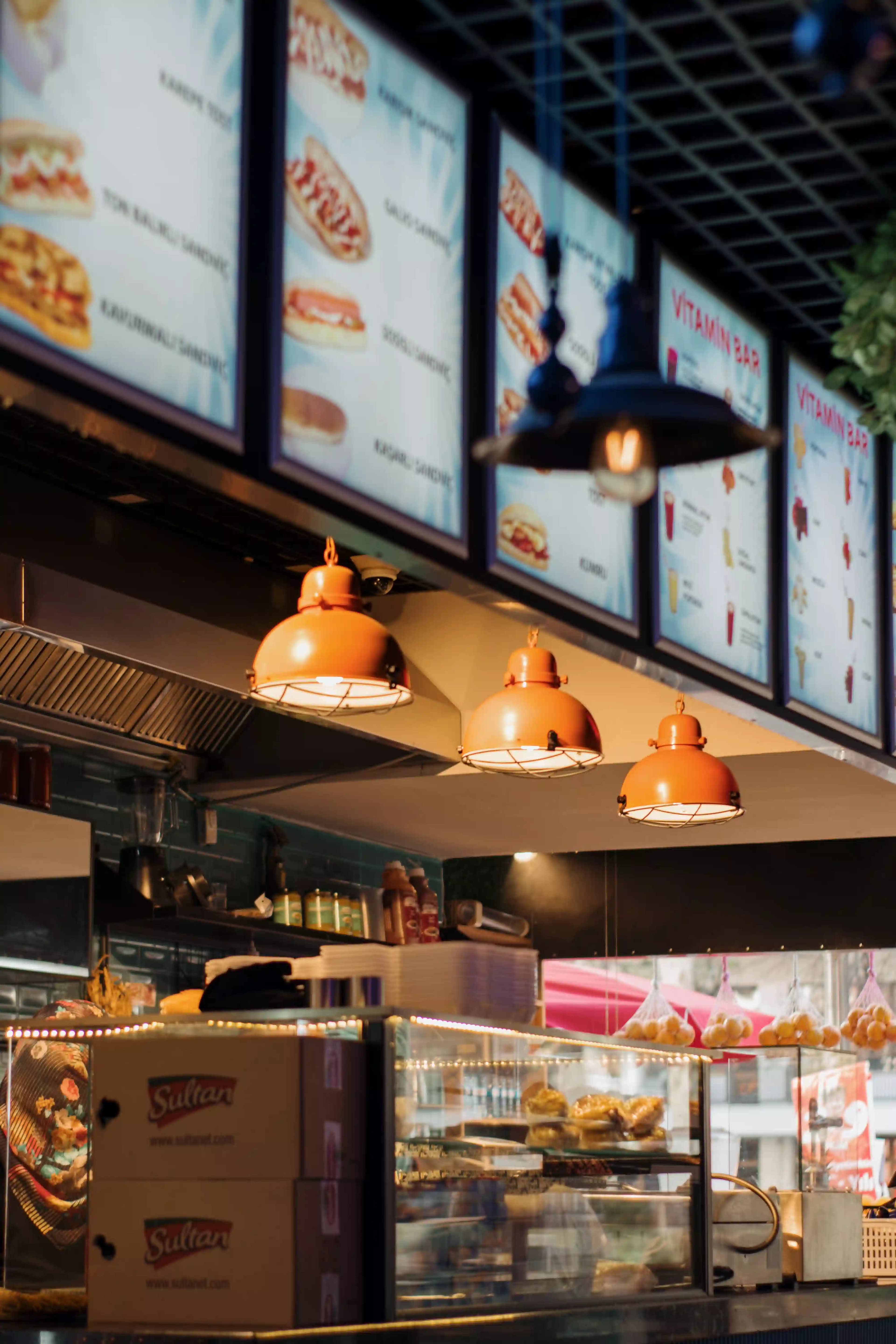 A food business counter with lit menu boards above it A food business counter with lit menu boards above it
