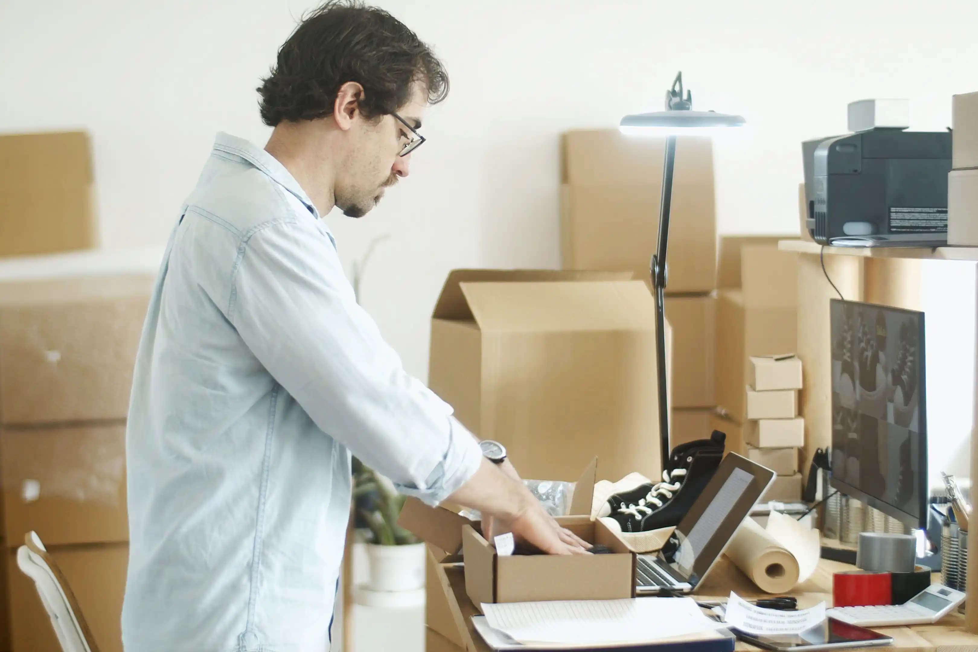 A small business owner packing an order at their desk A small business owner packing an order at their desk